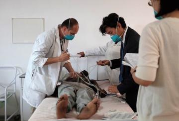 Dr. Danny Puga (left), and Dr. KJ Seung (right) conduct an electrocardiogram on one of the first multidrug-resistant tuberculosis patients to be enrolled in the endTB project in Lesotho. (Photo: Lan Nguyen / Partners In Health)